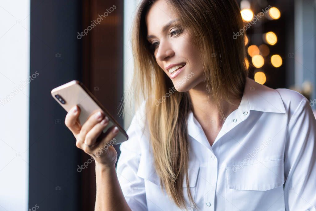 Young businesswoman using phone in coffee shop