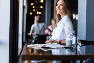 Sabahları restoranda kahve içen bir kadın.