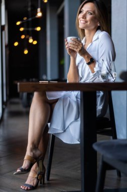 Sabahları restoranda kahve içen bir kadın.