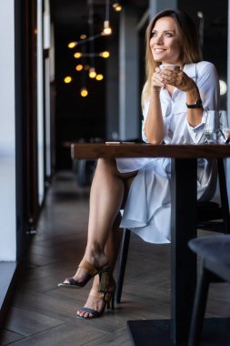 Sabahları restoranda kahve içen bir kadın.