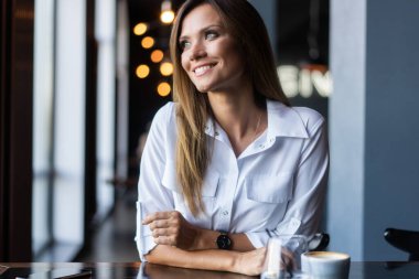 Sabahları restoranda kahve içen bir kadın.