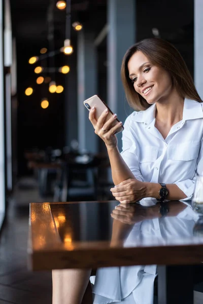 Kahve dükkanında telefon kullanan genç bir iş kadını. — Stok fotoğraf