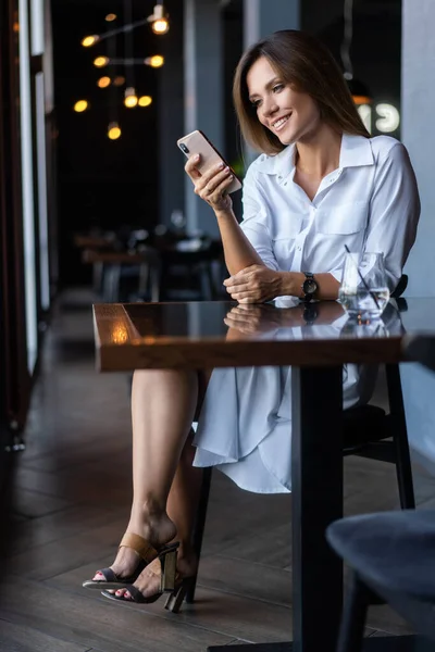 Wanita pengusaha muda menggunakan telepon di warung kopi — Stok Foto