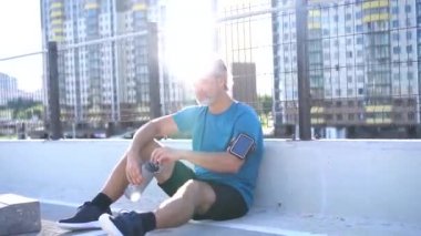 Spor giyim sektöründe modern bir adam, koşudan ya da kentsel alanda egzersiz yaptıktan sonra mola veriyor.