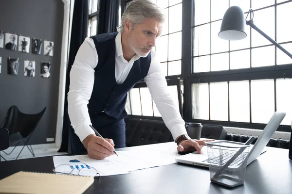 Pensive knappe gerijpte zelfverzekerde zakenman in trendy formele kleding controleren boekhoudkundige rapport — Stockfoto