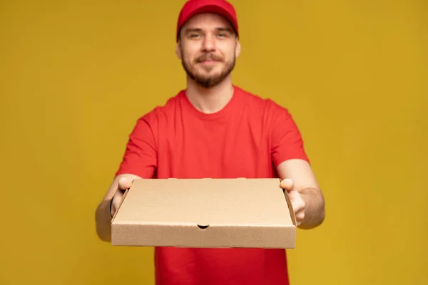 Glücklicher Mann vom Lieferdienst in rotem T-Shirt und Mütze, der Essen bestellt und Pizzakartons isoliert über gelb hält — Stockfoto