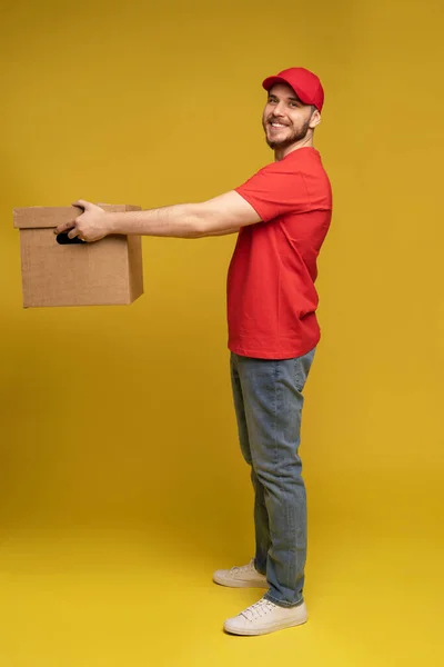 Liefermann mit Schachtel im Studio isoliert auf gelbem Hintergrund. — Stockfoto