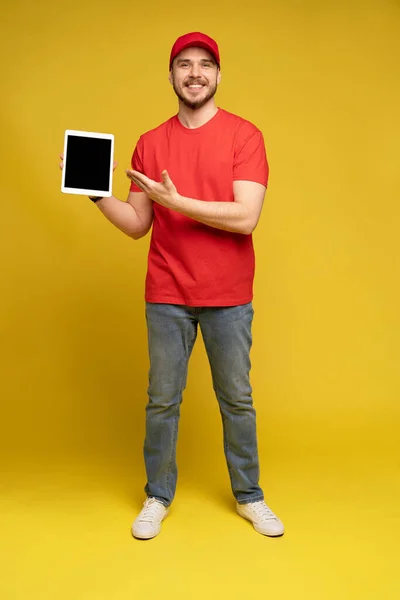 Happy delivery man met tablet in studio geïsoleerde gele achtergrond. — Stockfoto