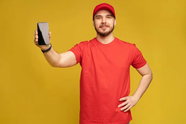 Junger Mann hält Smartphone isoliert auf gelb. — Stockfoto