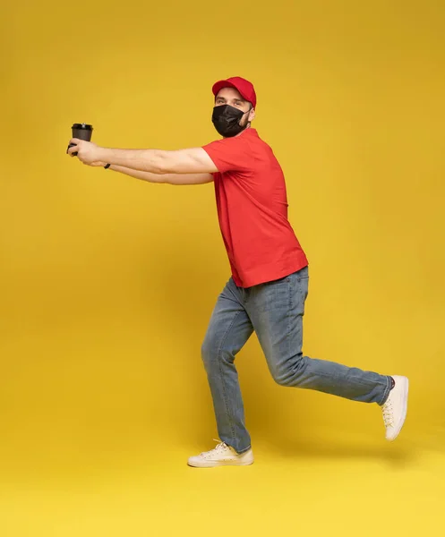Entrega homem em branco tampa vermelha t-shirt luvas de máscara uniforme isolado no estúdio de fundo amarelo — Fotografia de Stock