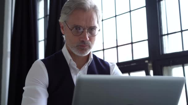 En gråhårig man som jobbar på en laptop. Seriös mogen man i elegant kostym skriva — Stockvideo