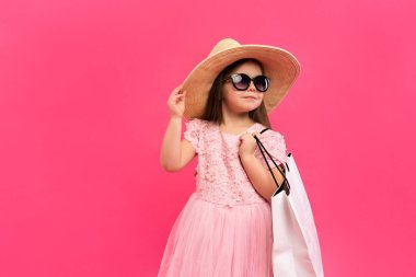 Pembe arka bahçesinde bir sürü alışveriş çantası olan bir kız..