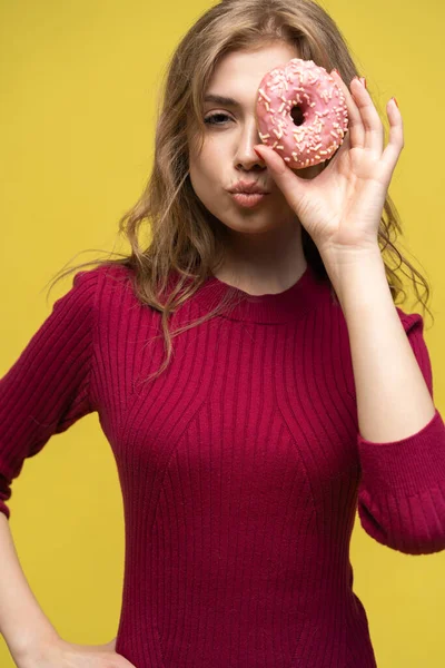 Sarı çöreğin üzerine gözlerini donut ile kapatan bir kadın.. — Stok fotoğraf