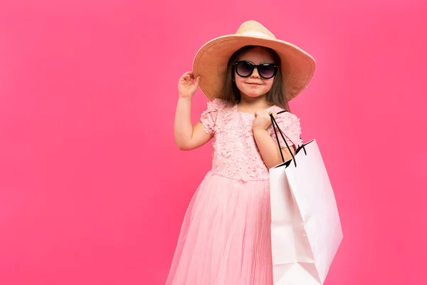 Chica con muchas bolsas de compras en vestido en fondo rosa. — Foto de Stock