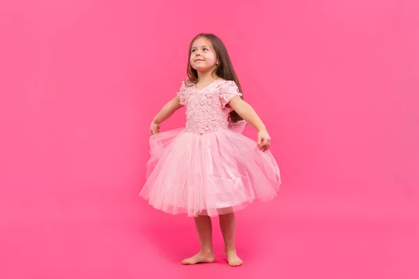 Nettes kleines Mädchen träumt davon, Ballerina zu werden. Kleines tanzendes Mädchen. Studioaufnahme über rosa Hintergrund — Stockfoto