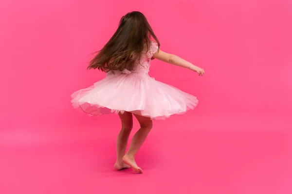 Schattig meisje droomt ervan ballerina te worden. Een klein dansmeisje. Studio shoot over roze achtergrond — Stockfoto