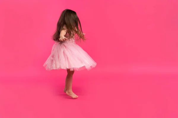 Мила дівчинка мріє стати балериною. Маленька танцююча дівчинка. Студія стріляти над рожевим тлом — стокове фото