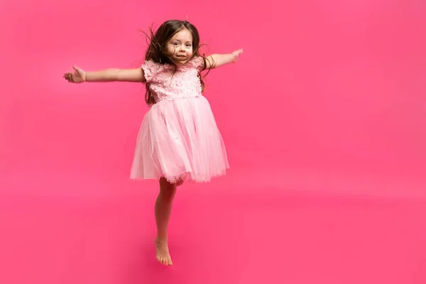 Nettes kleines Mädchen träumt davon, Ballerina zu werden. Kleines tanzendes Mädchen. Studioaufnahme über rosa Hintergrund — Stockfoto