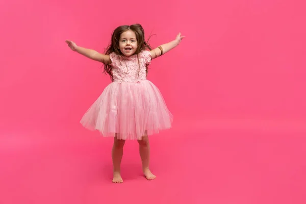 Nettes kleines Mädchen träumt davon, Ballerina zu werden. Kleines tanzendes Mädchen. Studioaufnahme über rosa Hintergrund — Stockfoto