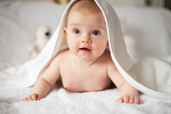 Baby girl is hiding under the white blanket. — Stock Photo, Image