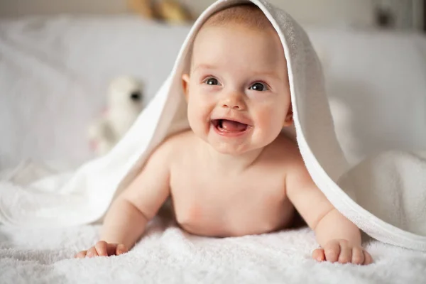 Baby girl is hiding under the white blanket. — Stock Photo, Image