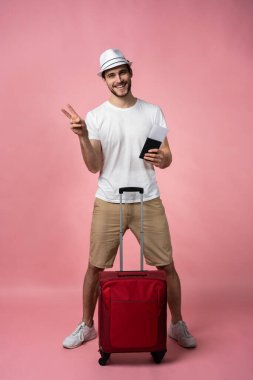 Bavulu, pasaportu ve arka planda bileti olan bir adam..
