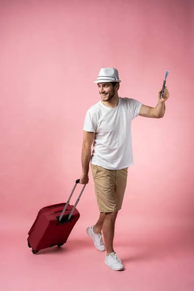 Podróżujący mężczyzna z walizką, paszportem i biletem na tle koloru. — Zdjęcie stockowe