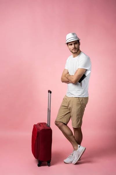 Чоловік мандрівник з валізою, паспортом та квитком на кольоровому фоні . — стокове фото