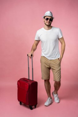 Bavulu, pasaportu ve arka planda bileti olan bir adam..
