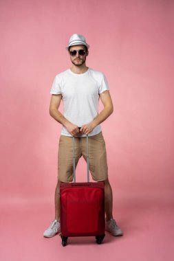 Bavulu, pasaportu ve arka planda bileti olan bir adam..