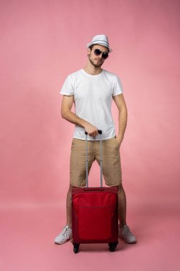 Bavulu, pasaportu ve arka planda bileti olan bir adam..