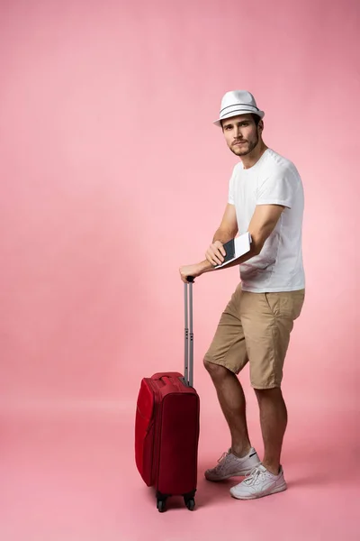 Man traveler with suitcase, passport and ticket on color background.