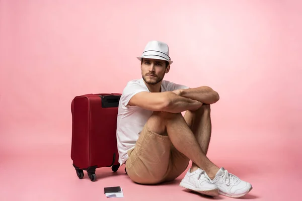 Ik wacht op de vlucht. Man reiziger zit op de vloer met koffer op kleur achtergrond. — Stockfoto