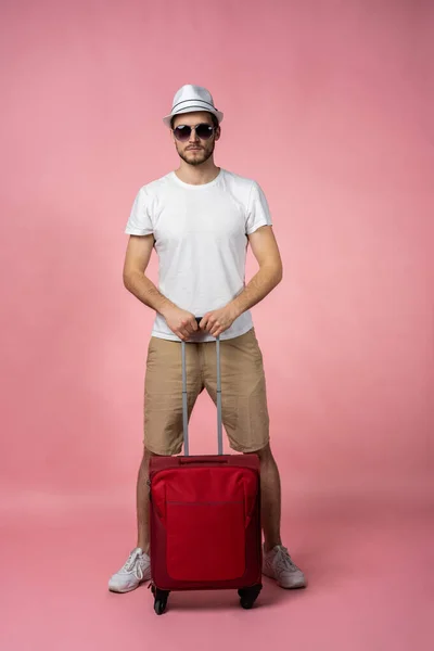 Чоловік мандрівник з валізою, паспортом та квитком на кольоровому фоні . — стокове фото