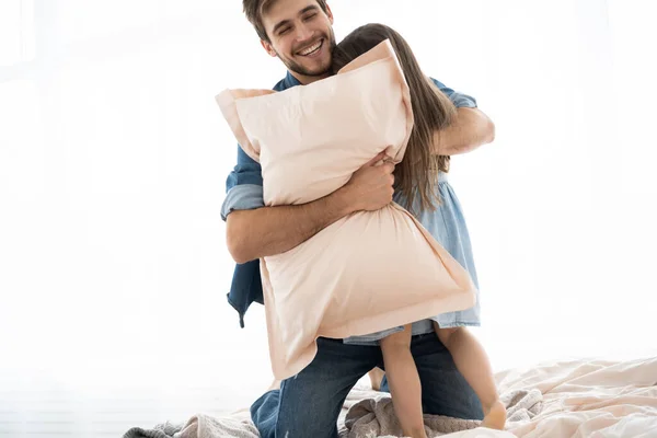 Pai feliz e filha jogando travesseiro luta na cama de manhã — Fotografia de Stock