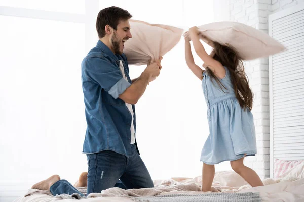 Felice padre e figlia a giocare a cuscino lotta a letto al mattino — Foto Stock