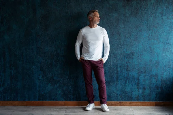 Casual Grey-haired Mature handsome man portrait over dark blue wall background. — Stock Photo, Image