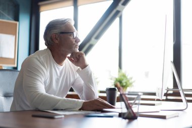Yoğun Yaratıcı Ofis 'te çalışan gri saçlı, olgun bir adam..