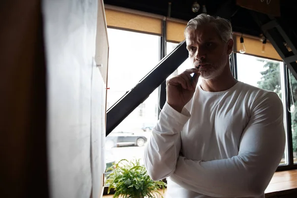 Casual Grey-haired Mature handsome man looking at his ideas written on paper and stuck to a wall. — Stock Photo, Image