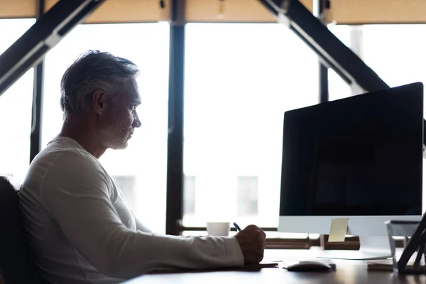 Casual grijs-harige volwassen man werken aan het bureau in drukke creatieve kantoor. — Stockfoto