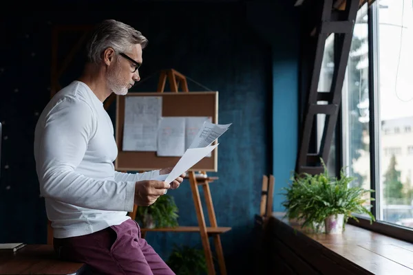 Casual de pelo gris Maduro hombre leyendo papel en su oficina. — Foto de Stock