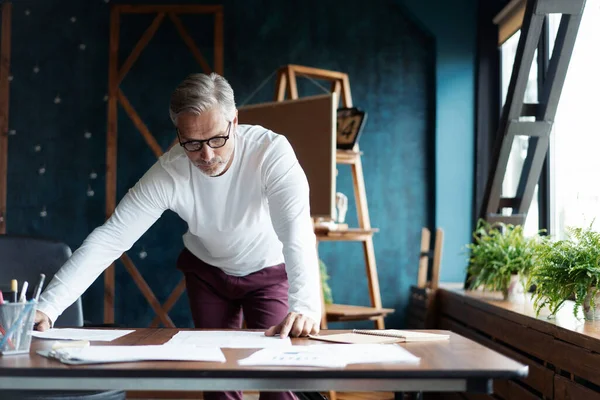 Casual Grey-haired Mature stilig arkitekt tittar på ritning med skiss av konstruktion på kontoret. — Stockfoto