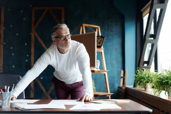 Casual Grey-haired Arquitecto guapo maduro mirando el plano con boceto de construcción en la oficina. —  Fotos de Stock