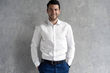 Yakışıklı adam gri arka planda tek başına mavi takım elbise giyiyor..