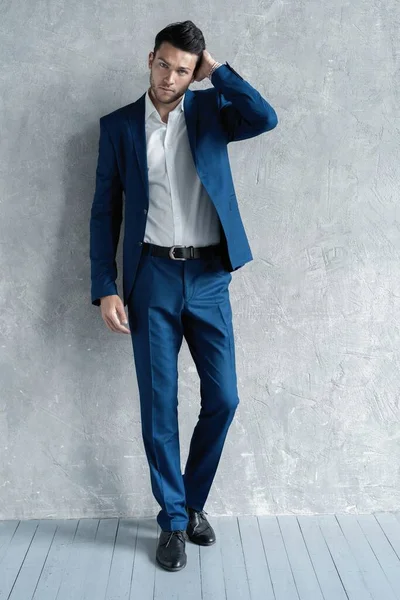 ハンサムな男の完全な長さは灰色の背景に隔離された青いスーツを身に着けて. — ストック写真