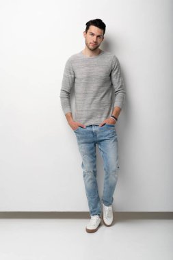 Beyaz arka plandaki yakışıklı genç adam kameraya bakıyor. Mutlu adam gülümsüyor