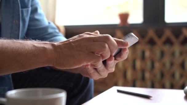 Gros plan mains de l'homme mature à l'aide d'un smartphone, en tapant un message sur le téléphone mobile. — Video