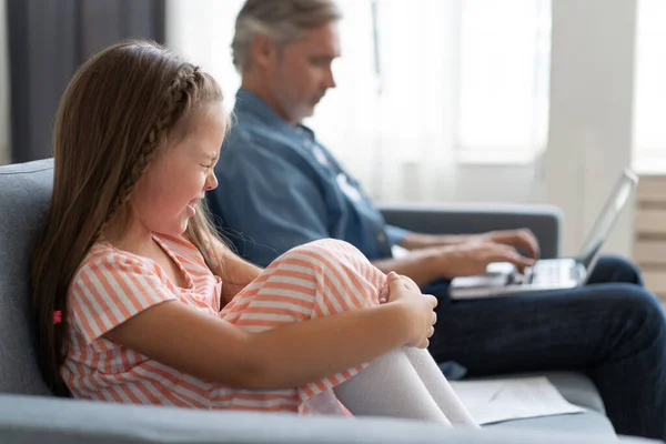 No Time For Child. Grey-haired dad busy with laptop, working online at home, sad bored offended daughter sitting near by — Stock Photo, Image