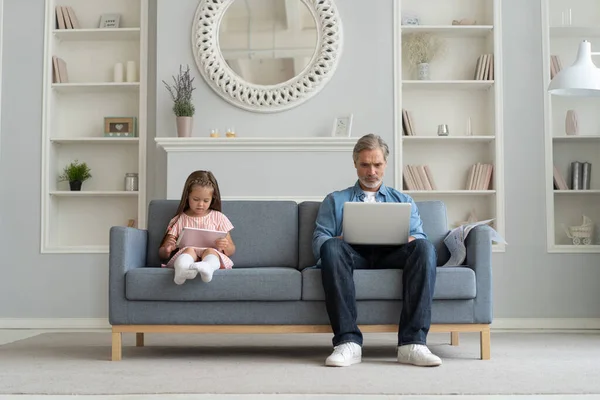 Отец и дочь используют электронные устройства дома. — стоковое фото