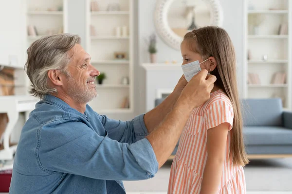 Père ajustant le masque protecteur à sa fille de 6 ans avant de sortir pendant la pandémie Covid-19. — Photo